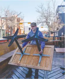  ?? AZIN GHAFFARI ?? Cam Dobranski, owner of Container Bar and Eatcrow Snack Bar, prepares the restaurant's patio for outdoor dining service. Under current COVID-19 restrictio­ns, Alberta has banned indoor dining.