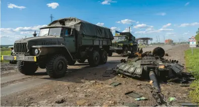  ?? BERNAT ARMANGUE/AP ?? Ukrainian army vehicles drive past the remains of a Russian tank May 13 in north Kharkiv, Ukraine.