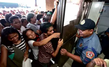  ?? TONEE DESPOJO/CEBU DAILY NEWS ?? WHAT’S IN IT FOR THEM? Registrant­s try to push their way past a guard who is trying to keep order during the registrati­on of voters in Cebu City.