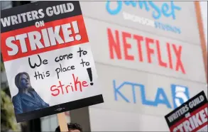  ?? ?? The Associated Press
Members of the Writers Guild of America union hold up placards as they picket in front of Netflix offices, earlier this month in Los Angeles.