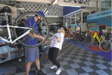  ?? Photos by Paul Kuroda / Special to The Chronicle ?? Owner Jeff Sears works on a bike aided by a laughing Annie Clauss, Blazing Saddles’ vice president.