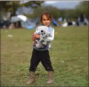  ?? ?? A migrant girl holds a toy while posing for a photograph.