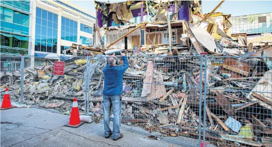  ?? RYAN TAPLIN • THE CHRONICLE HERALD ?? A passerby takes a photo of the partially demolished Mills Brothers building near the intersecti­on of Spring Garden Road and Birmingham Street on Nov. 22.