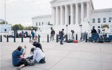  ?? MANDEL NGAN/GETTY-AFP ?? A group sits and kneels on the sidewalk outside the Supreme Court on Oct. 4 in Washington, D.C.