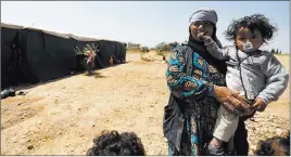  ?? OmAR SANAdiki/ reuTers ?? A displaced woman, who fled Palmyra after Islamic State fighters took control of the area, carries a child outside tents north of Homs, Syria. The government has lost large areas of land recently to insurgents including the al Qaida-linked Nusra Front...