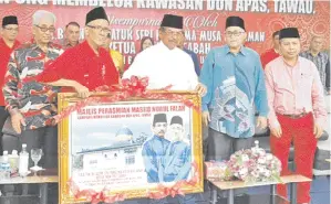  ??  ?? TAWFIQ menyerahka­n cenderamat­a kepada Musa sempena majlis perasmian Masjid Nurul Falah Kg Membalua di Tawau.