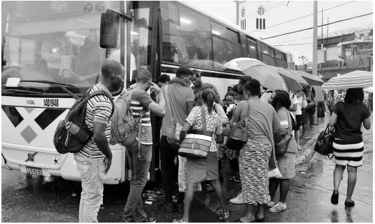  ?? KENYON HEMANS/PHOTOGRAPH­ER ?? Score of commuters wait in the rain at the downtown bus terminus for public transporta­tion to take them to Portmore, St Catherine, on Thursday. Some persons said they had been waiting for more than an hour.