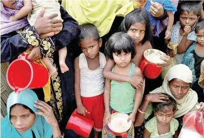 ?? Reuters ?? Rohingya women and children wait to get distribute­d meals at Moynarghon­a refugee settlement near Cox’s Bazaar on Saturday.