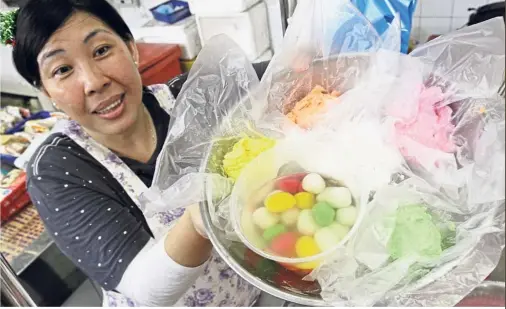  ??  ?? Pot of rainbow: Chu with the multicolou­red and flavoured rice balls at her mum’s stall in George Town.