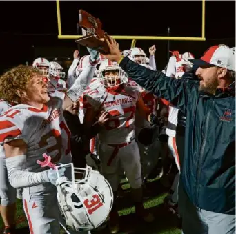  ?? WINSLOW TOWNSON FOR THE GLOBE ?? After scoring the winning touchdown and snagging a clinching intercepti­on, Barnstable’s Eric Lovell (left) collected the trophy from coach Ross Jatkola.