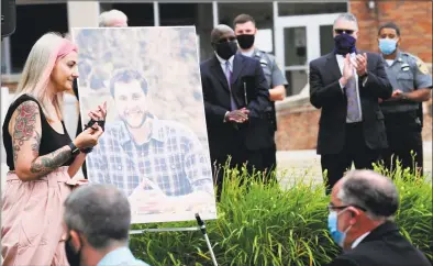  ?? Matthew Brown / Hearst Connecticu­t Media ?? Katie Coehlo, of Bethel, passes a portrait of her late husband, probation officer Jonathan Coehlo, after thanking the attendees of a memorial service outside the state Superior Courthouse in Stamford on Wednesday.