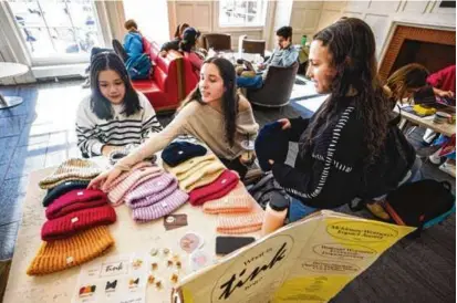  ?? PHOTOS BY NICK DENTAMARO/BROWN UNIVERSITY ?? Brown University students, from left, Tiffany Ko, Anna Lapre, and Emily Perelman sell hats in the campus center as part of the nonprofit Tink Knit.