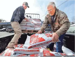  ?? SCOTT MASON/THE WINCHESTER STAR VIA AP ?? Clayton Smith, left, and Grover Loy load bags of salt in Winchester, Va., as the East’s fourth nor’easter of the month approached.