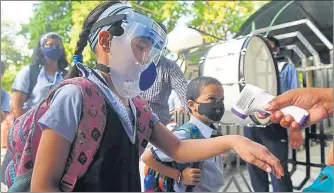  ?? DEEPAK GUPTA/ HT PHOTOS ?? Students being checked for fever before they enter the school premises on Wednesday and (below) a student listens attentivel­y to the teacher in class.