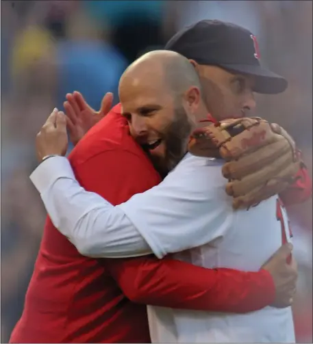 ?? STUART CAHILL — BOSTON HERALD ?? Dustin Pedroia, right, hugs Alex Cora after the first pitch as the Red Sox pay tribute to Pedroia prior to a June 25, 2021 game at Fenway Park.