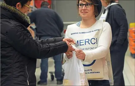  ??  ?? Une jeune femme participe dans un supermarch­é à une collecte pour la banque alimentair­e du Nord, à Lille.
