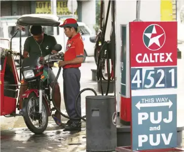  ?? REUTERS ?? A tricycle driver gets his vehicle filled with gasoline in a Caltex gas station in Quezon City, Metro Manila.
