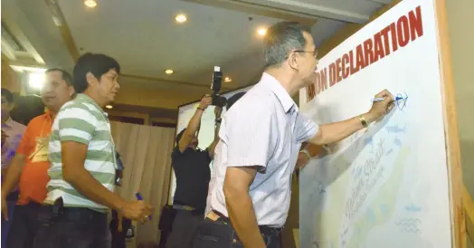  ?? (SUN.STAR FOTO/AMPER CAMPAÑA) ?? SUPPORT. DENR 7 Director Isabelo Montejo (right) signs the declaratio­n of commitment board to help protect Tañon Strait. The signature campaign culminated the three-day summit yesterday.