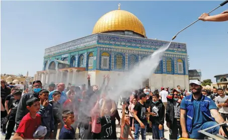  ?? AFP ?? A man sprays Palestinia­ns with water to cool them off as they gather outside the Dome of the Rock at the Al-Aqsa Mosque compound in Jerusalem’s Old City.