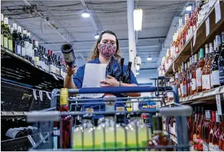  ?? PHOTOS BY ALYSSA POINTER/ ALYSSA. POINTER@ AJC. COM ?? Cashier Dilyana Kovachevam­aneuvers through the aisles to fill a customer’s call- in order Thursday at the Tower Beer, Wine& Spirits store in the Lindbergh/ Morosgo neighborho­od. Kovacheva also fills orders for delivery, which began on asmall scale lastweek.