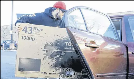  ?? ERIC WYNNE/THE CHRONICLE HERALD ?? Evan White loads his new 43-inch television into his car on Tuesday, after taking advantage of a Boxing Day Sale at Best Buy in Dartmouth Crossing Wednesday.