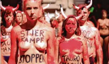  ?? Foto: Ander Gillenea, afp ?? Zum Teil barbusig protestier­en Tierschütz­er in Pamplona gegen die traditione­lle Stierhatz.