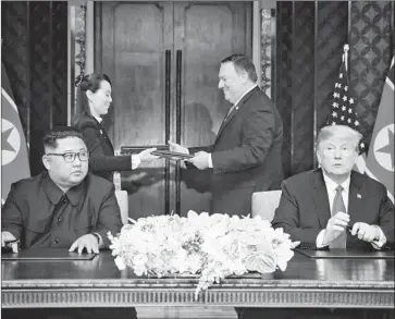  ?? Kevin Lim AFP/Getty Images ?? WITH NORTH KOREAN leader Kim Jong Un and President Trump in attendance, Kim’s sister Kim Yo Jong and Secretary of State Mike Pompeo exchange documents at a signing ceremony on Sentosa Island.