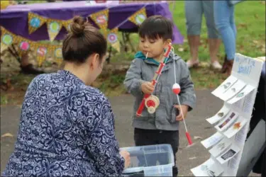  ?? MICHILEA PATTERSON — FOR MEDIANEWS GROUP ?? Sarah Crothers, education coordinato­r for the Schuylkill River Greenways National Heritage Area, helps a child with a watershed game during a festival at Riverfront Park in Pottstown. During the game, children learned what items are good to see in the water such as fish as opposed to items we don’t want to see in the water such as trash.