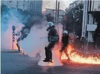  ?? PETROS GIANNAKOUR­IS THE ASSOCIATED PRESS ?? Riot police officers try to avoid patrol bombs thrown by protesters outside the Greek Parliament during a protest against new protest law in Athens on Thursday.