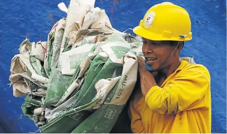  ?? /Reuters ?? Building blocks: A worker carries cement bags at a constructi­on site of a new apartment in Jakarta, Indonesia. Positive growth rates in many parts of the world and improved economic conditions are expected to help drive new infrastruc­ture projects, which will in turn boost global cement demand.