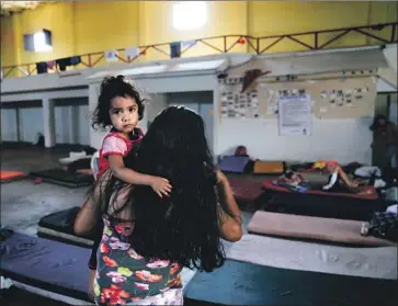  ?? Photograph­s by Nelvin C. Cepeda San Diego Union-Tribune ?? CLEMENTA PEREZ carries daughter Jaily, 2, at the Prodigal Son shelter in Mexicali, Mexico. Residents who can’t afford the 100 pesos charged a week for room and board are required to help clean and cook meals.