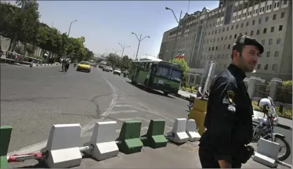  ?? PHOTO/ ?? A police officer stands guard as vehicles drive in front of Iran’s parliament building in Tehran, Iran, on Thursday. Police increased their patrols in the streets and subway stations of Tehran on Thursday, a day after a pair of stunning Islamic...