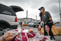  ??  ?? Janet Splitek picks up potato sacks to place in a vehicle. The Food Bank holds mega events at locations around the city.