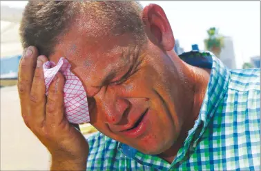  ?? Associated Press photo ?? Steve Smith wipes sweat from his face as temperatur­es climb to near-record highs in Phoenix on Monday. Monday’s temperatur­e was forecast to hit 48 C while today it was expected to reach 49 C.