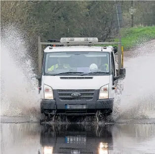  ??  ?? Braving floods in Sutton Gault, Cambridges­hire, as heavy rain continues this week