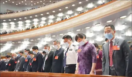  ?? WANG YUGUO / XINHUA ?? Participan­ts pay a silent tribute to the martyrs and compatriot­s who fell victim to the COVID-19 pandemic while attending the third session of the 13th National People’s Congress in the Great Hall of the People in Beijing on Friday.