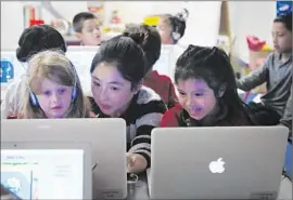  ?? Katie Falkenberg
Los Angeles Times ?? TEACHER MICHELLE LEE, center, works with students who have access to computers but who also use glue sticks, markers and paint.