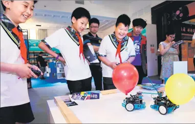  ?? JIN LIWANG / XINHUA ?? Students control robot combatants in an attempted to pop each other’s balloons at the Cultural Palace of Nationalit­ies in Beijing on Saturday as the 17th National Science Week began.