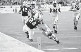  ?? MICHAEL LAUGHLIN/STAFF PHOTOGRAPH­ER ?? Miami running back Travis Homer reaches for the end zone on a 19-yard run late in the game against Virginia on Saturday at Hard Rock Stadium in Miami.