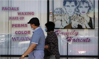  ?? Photograph: Richard Vogel/AP ?? A couple walk by a closed hair salon in Los Angeles on Tuesday. Unless lawmakers step in, the $600 weekly payment will expire on 31 July.
