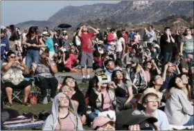  ?? ASSOCIATED PRESS ?? A crowd gathers in front of the Hollywood sign at the Griffith Observator­y to watch the solar eclipse in Los Angeles on Monday.