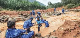  ?? PTI/REUTERS ?? ( Above) Rescue workers search for bodies of missing persons after a landslide, triggered by heavy rain and flood, at Nenmara in Palakkad in Kerala on Friday. ( Left) People are airlifted by the Navy during a rescue operation at a flooded area