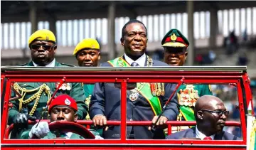  ??  ?? Mnangagwa (centre) inspects the guard of honour from a car during the Defence Forces Day celebratio­ns held at the National Sports Stadium in Harare. — AFP photo