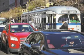  ?? Amy Osborne / Special to The Chronicle 2016 ?? A Lyft car goes up Market Street with the F-Market train nearby. Traffic planners didn’t foresee the rise of ride hailing when they reduced lanes for cars.