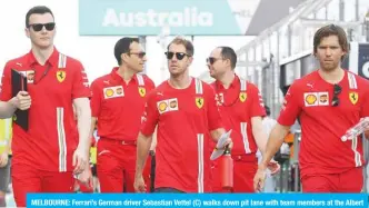  ??  ?? MELBOURNE: Ferrari’s German driver Sebastian Vettel (C) walks down pit lane with team members at the Albert Park circuit ahead of the Formula One Australian Grand Prix in Melbourne yesterday. — AFP