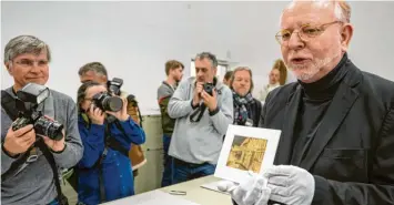  ?? Fotos: Peter Kneffel, dpa/Hans-Joachim Becker ?? Im Archiv des Deutschen Museums in München lagern hoch interessan­te Dokumente. Darunter das erste Foto von München, das der langjährig­e Archivleit­er Wilhelm Füßl in der Hand hält.