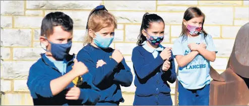  ??  ?? Members of the St. Damian first grade music class sign the word “love” while performing the hymn “Jesus Loves Me” Thursday outside the Oak Forest school.