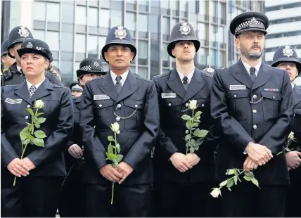  ?? Dan Kitwood ?? > Police officers hold white roses on Westminste­r Bridge yesterday during a vigil to remember the victims exactly one week after the Westminste­r terrorist attack