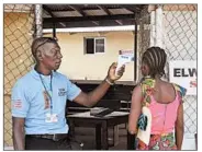  ?? ABBAS DULLEH/AP ?? A family member of a 15-year-old boy who has Ebola has her temperatur­e measured by a health worker in Monrovia.