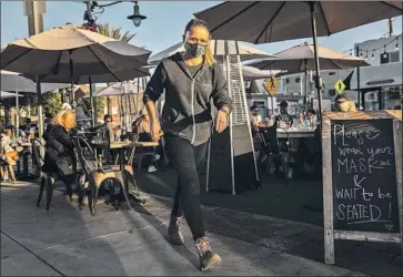  ?? Jay L. Clendenin Los Angeles Times ?? A MASKED and shielded server works at the Hook & Plow in Hermosa Beach last Wednesday, the last day outdoor dining was allowed in L. A. County for at least three weeks because of the increase in COVID- 19 cases.